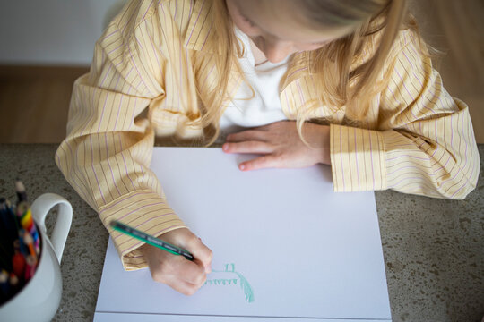 Over Shoulder View of Young Girl Drawing with Pencil at Home.