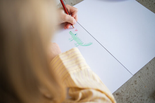 Close-up of Child's Hand Drawing with a Pencil on White Paper