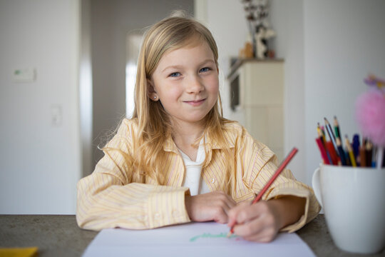 Happy Young Girl Smiling While Drawing or Doing Homework.