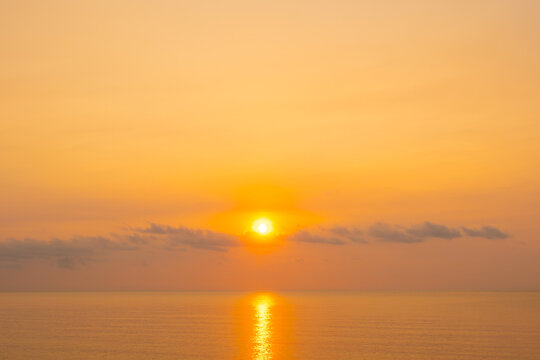 nature sky breathtaking golden sunset over a calm ocean, with the entire sky and water bathed in brilliant shades of yellow and orange. Streaky clouds enhance the dramatic displa
