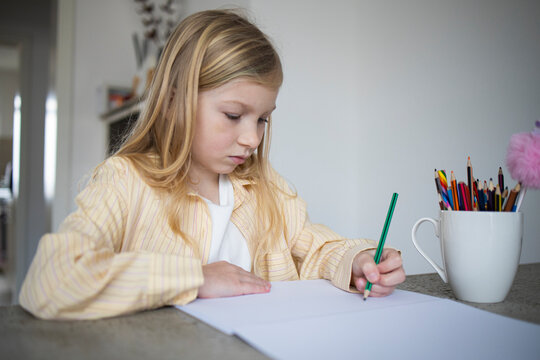 Young Girl Concentrating While Drawing or Doing Homework at Home.