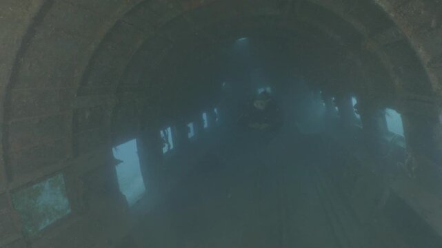 log footage of scuba divers  exploring an air craft wreck underwater. Ocean pollution. metal on ocean floor
