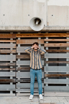 Man with hands over his ears standing beneath loudspeaker