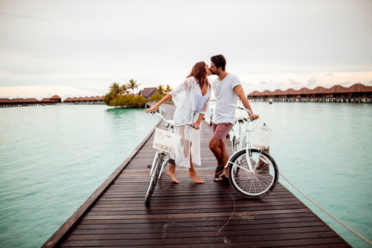 Couple with bicycles kissing on a jetty in the sea, Maguhdhuvaa Island, Gaafu Dhaalu Atoll, Maldives