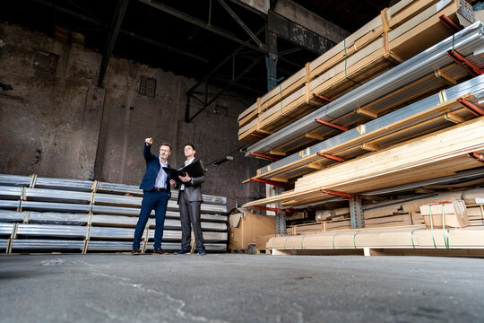 Two businessmen with folder talking in an old storehouse