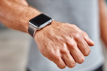 Close up of a man's wrist wearing a silver smart watch with a gray band, showcasing modern technology and connectivity in everyday life with health tracking.