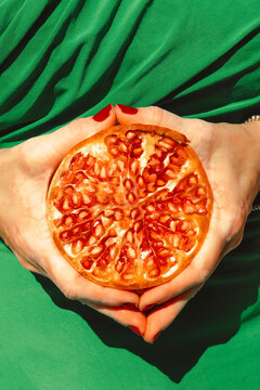 Hands of woman holding halved pomegranate