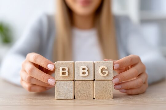 Woman holding wooden blocks spelling out BBG, business development, team growth, new strategy, successful management team, and building blocks for progress.