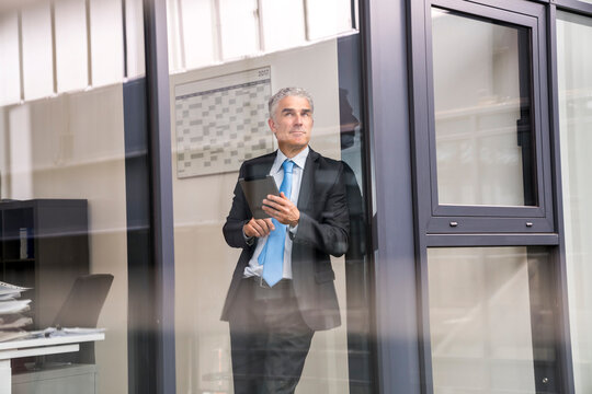 Mature businessman in office using digital tablet