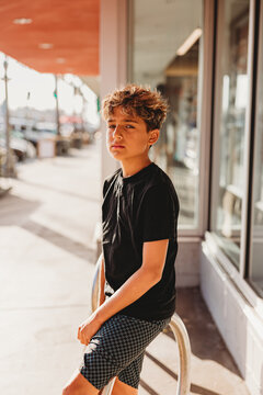 Serious boy standing on a sidewalk looking at camera.