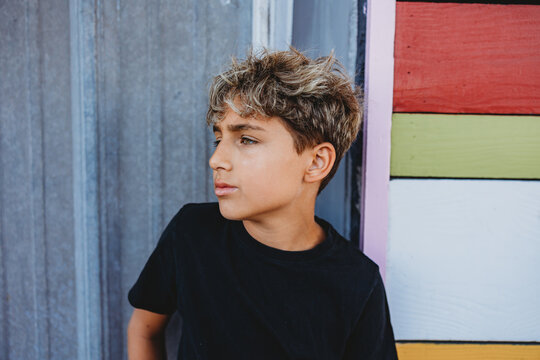 Profile of a boy in front of a mix of metal and colorful walls.
