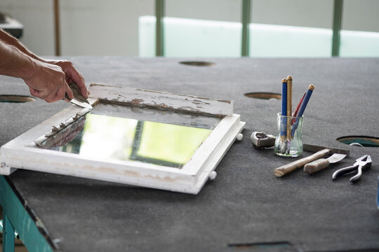 Glazing, glazier during work with putty on window pane