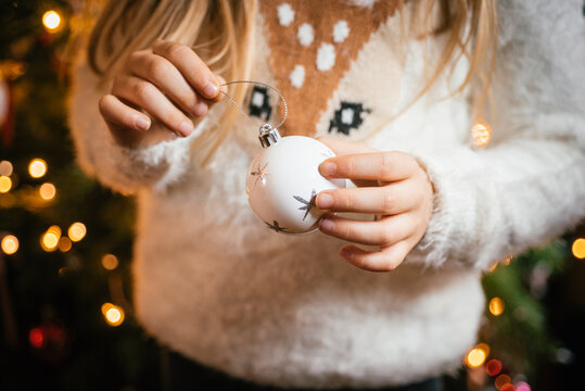 Decorating the christmas tree, girl holding a white bauble with silver stars