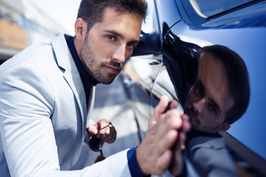 Young businessman stroking his polished car
