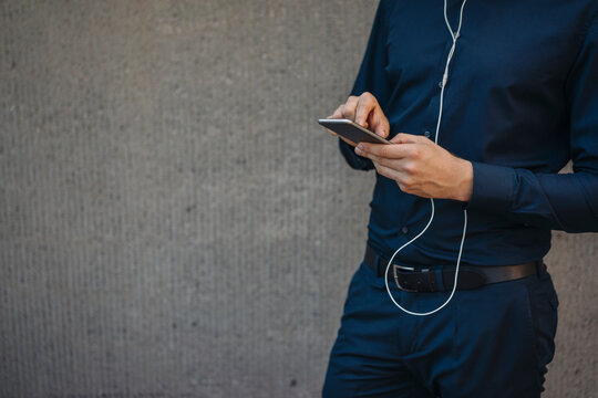 Businessman holding smartphone with connected earphones