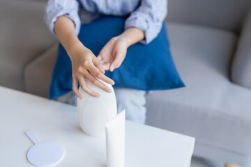 Obraz premium Asian Woman Applying Lotion to Hands, Self-Caring at Home