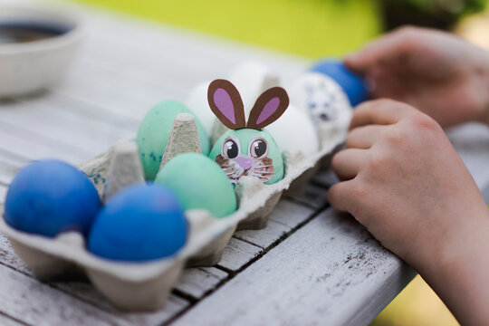 Close-up of girl decorating Easter egg on garden table