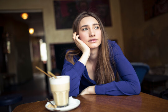 Young woman sitting at table in a cafe looking sideways