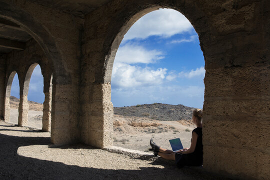 Spain, Tenerife, Abades, Sanatorio de Abona, woman sitting in ghost town building using laptop