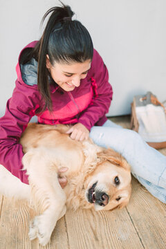 Happy young woman stroking and playing with her golden retriever dog