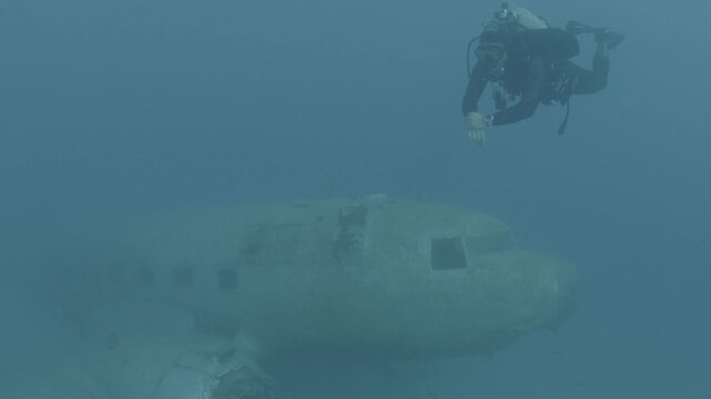 log footage of scubadivers exploring airplane wreck underwater