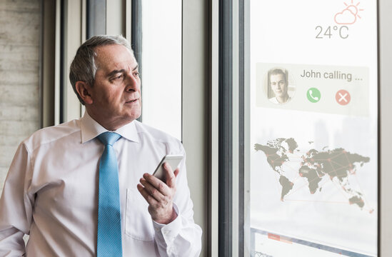 Businessman receiving a call on windowpane with world map in office