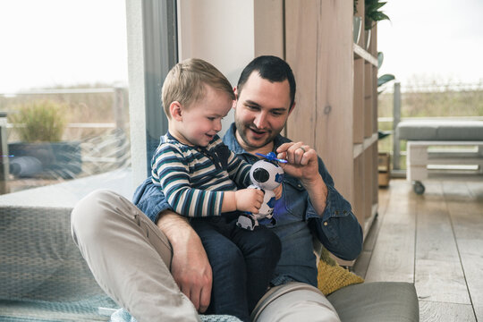 Father and son playing with a toy robot at home