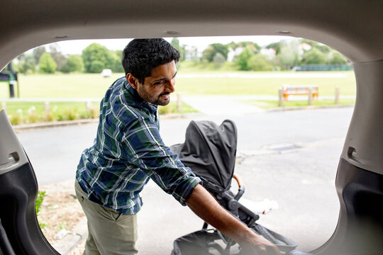 Indian man unloading pram from car boot