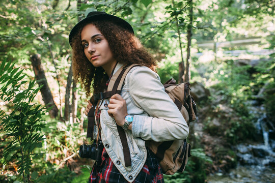Portrait of teenage girl with backpack and camera in nature