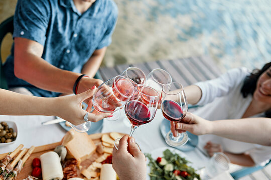 Friends having dinner at a lake clinking wine glasses