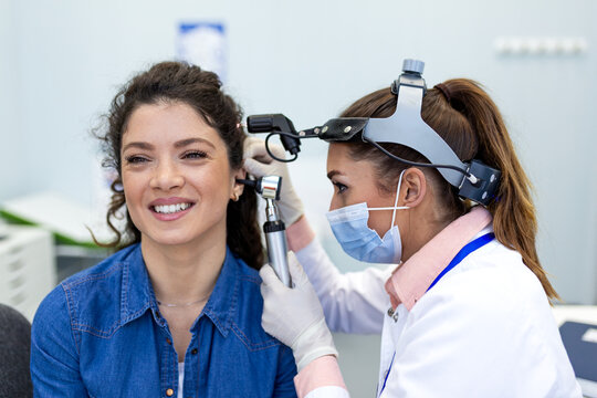 Ear examination with otoscope. Female doctor checking patient's ear, Healthcare and Medicine concept. ENT specialist performing otoscopy and ear health checkup for young woman in medical office.