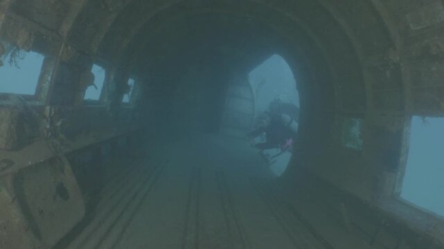 log footage of scubadivers exploring airplane wreck underwater