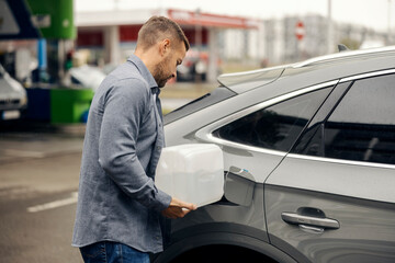 Man pouring adblue fluid from canister into car tank