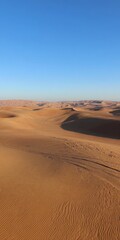 Desert sand dunes creating patterns under blue sky