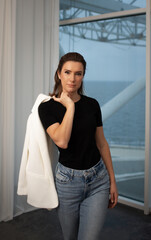 Fototapeta premium Confident woman portrait by window wearing white blazer over shoulder