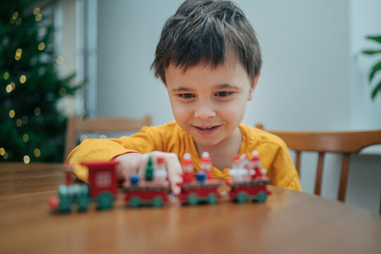 Smiling child playing with toy Christmas train at home during holiday