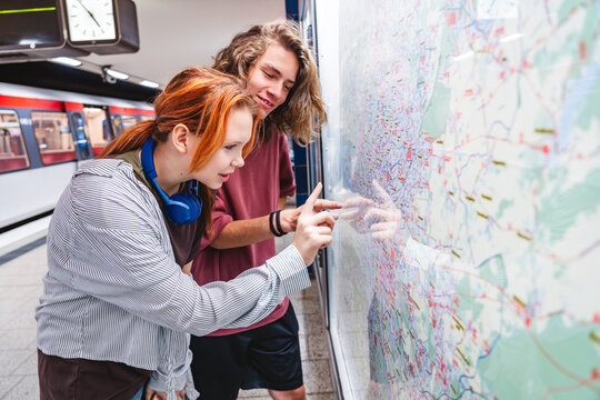 Young people planning route at metro station map during urban commute