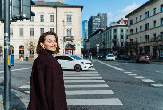 Smiling woman on city street crosswalk with urban architecture