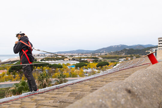 Construction worker with safety harness working on rooftop