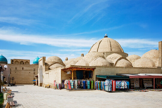 Historic Toki Telpak Furushon domed bazaar in Bukhara, Uzbekistan with historic domed market halls, stalls selling colorful textiles, and authentic Silk Road atmosphere.
