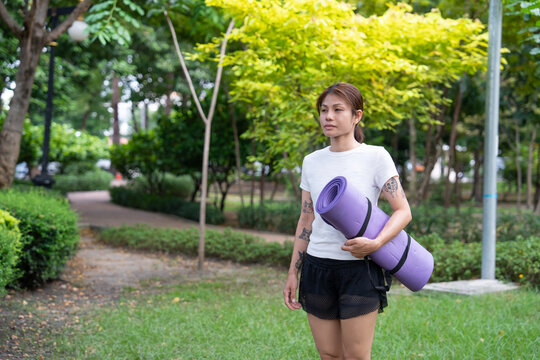 Beautiful young woman practicing Padmasana on yoga mat outdoors, space for text.