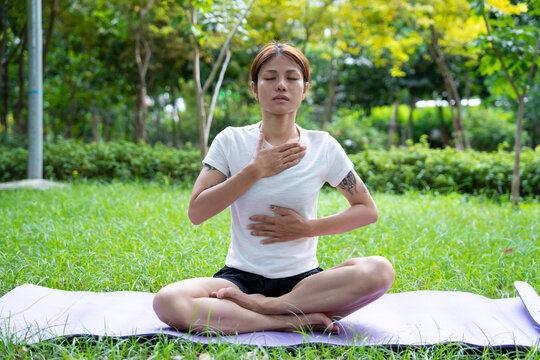 Beautiful young woman practicing Padmasana on yoga mat outdoors, space for text.