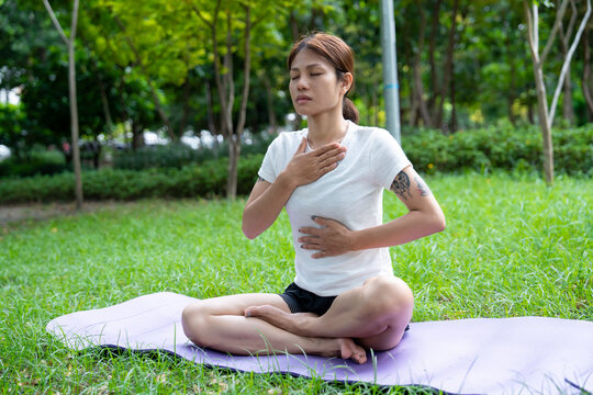 Beautiful young woman practicing Padmasana on yoga mat outdoors, space for text.