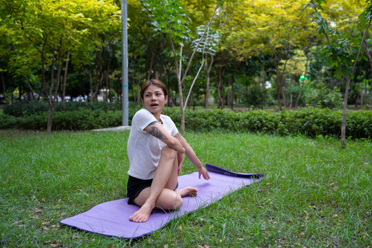 Beautiful young woman practicing Padmasana on yoga mat outdoors, space for text.
