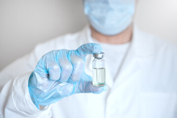 Doctor holding  clear glass bottle  with medicine or vaccine