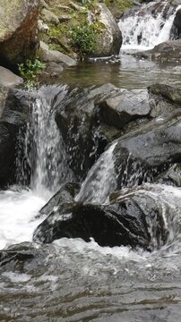 Closeup of a beautiful mountain river flowing over natural rocks with stunning texture and depth. Ideal for vertical mobile advertising, travel branding, and immersion background visuals.