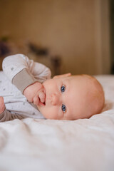 Cute newborn baby with bright blue eyes lying comfortably on a cozy white blanket, wearing a light gray outfit, symbolizing innocence, warmth, and early childhood calmness