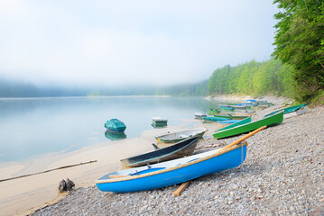 stony lake shore Sylvensteinsee, with rowing boats. foggy morning. scenery upper bavaria