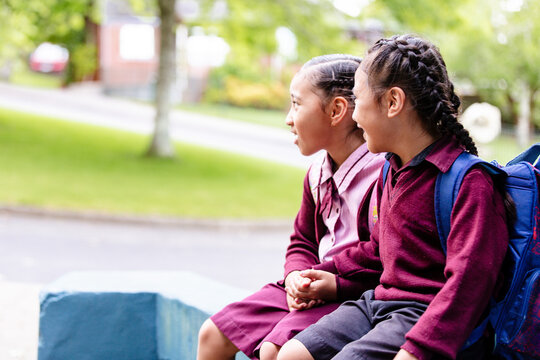 Samoan children in school uniform sitting on the blue concrete ledge