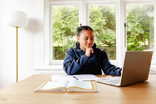Teenage Samoan girl doing her homework on the table using laptop